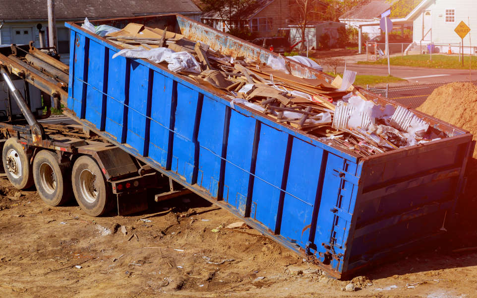 Industrial garbage bin blue construction debris container filled with rock and concrete rubble.
